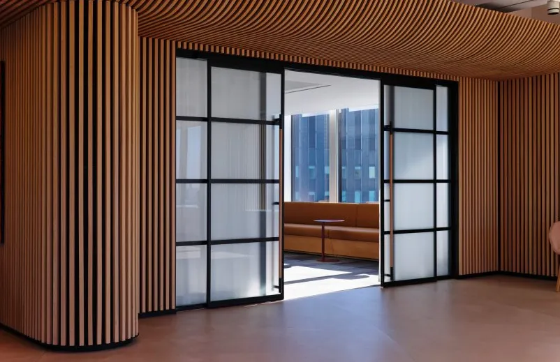 Puertas corredizas de vidrio esmerilado rodeadas de listones verticales de roble