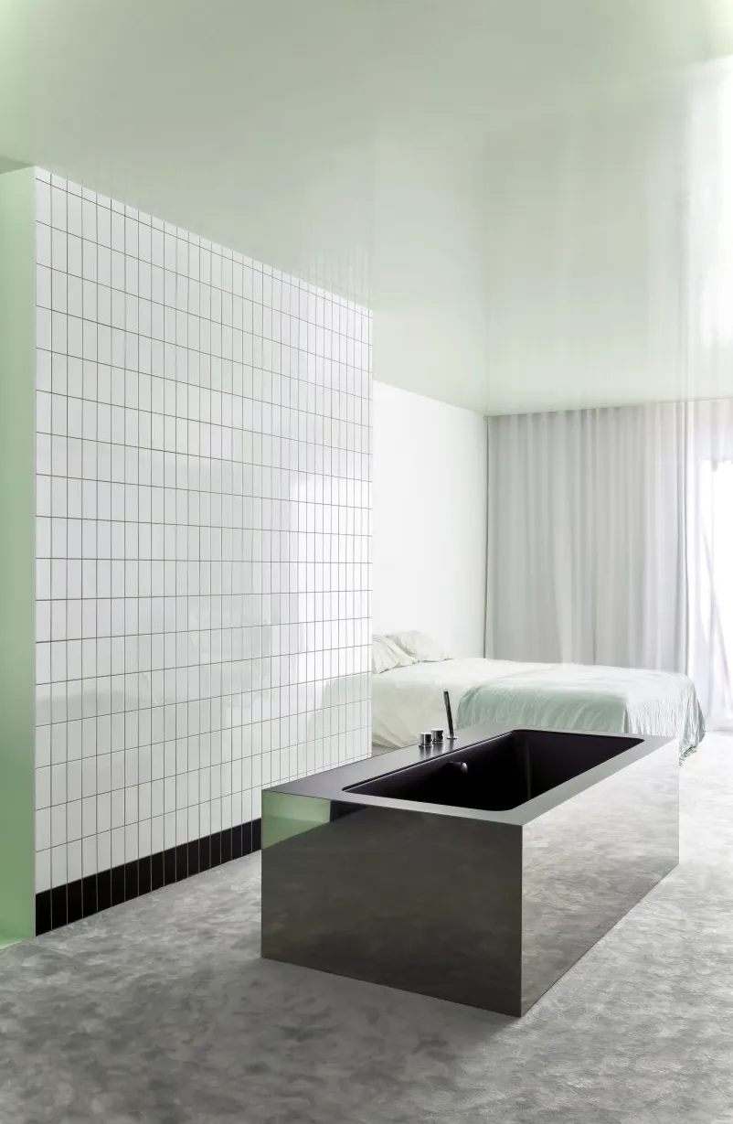 Dormitorio y baño adyacente de planta abierta en el Apartamento A de Atelier Dialect con bañera rectangular