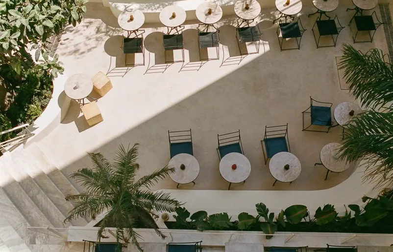 Vista aérea de un patio con mesas de café y palmeras.