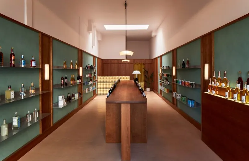 Tienda de botellas diseñada por Wes Anderson con mostrador central de madera y expositores a ambos lados.