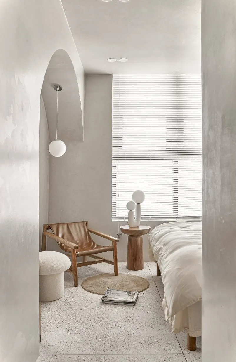 Dormitorio blanco con muebles esculturales de madera.