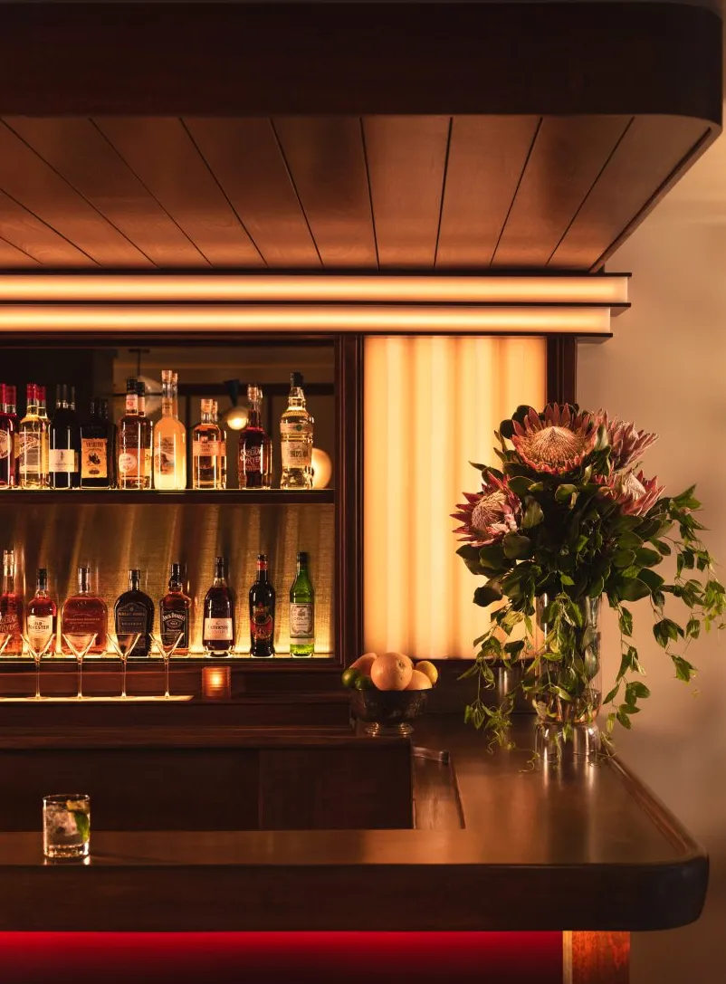Esquina de bar con paneles de madera e iluminación personalizada.