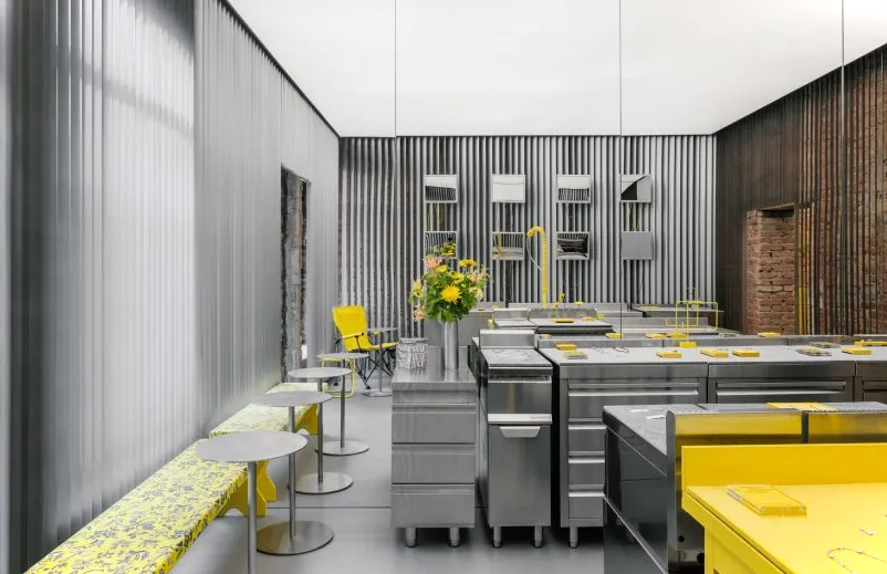 Interior de tienda con muebles de acero inoxidable y fregadero amarillo.