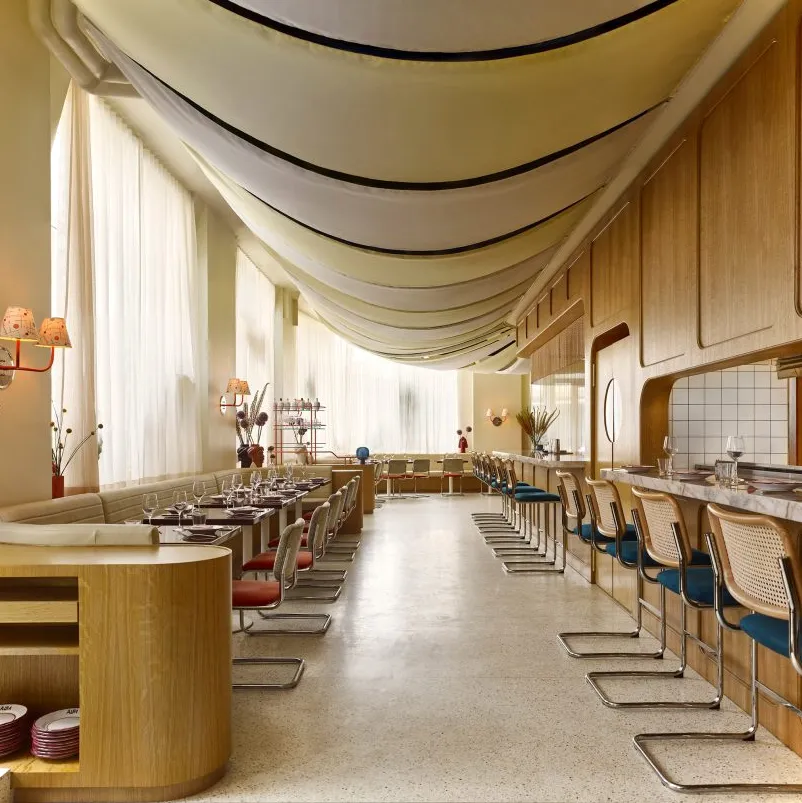 Restaurante luminoso con asientos a ambos lados y paneles de tela en el techo.