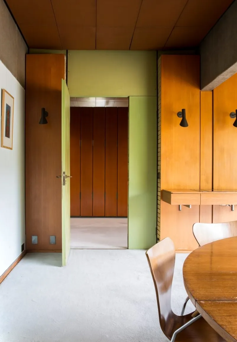 Fotografía que muestra una habitación con paneles de madera y una pared verde.