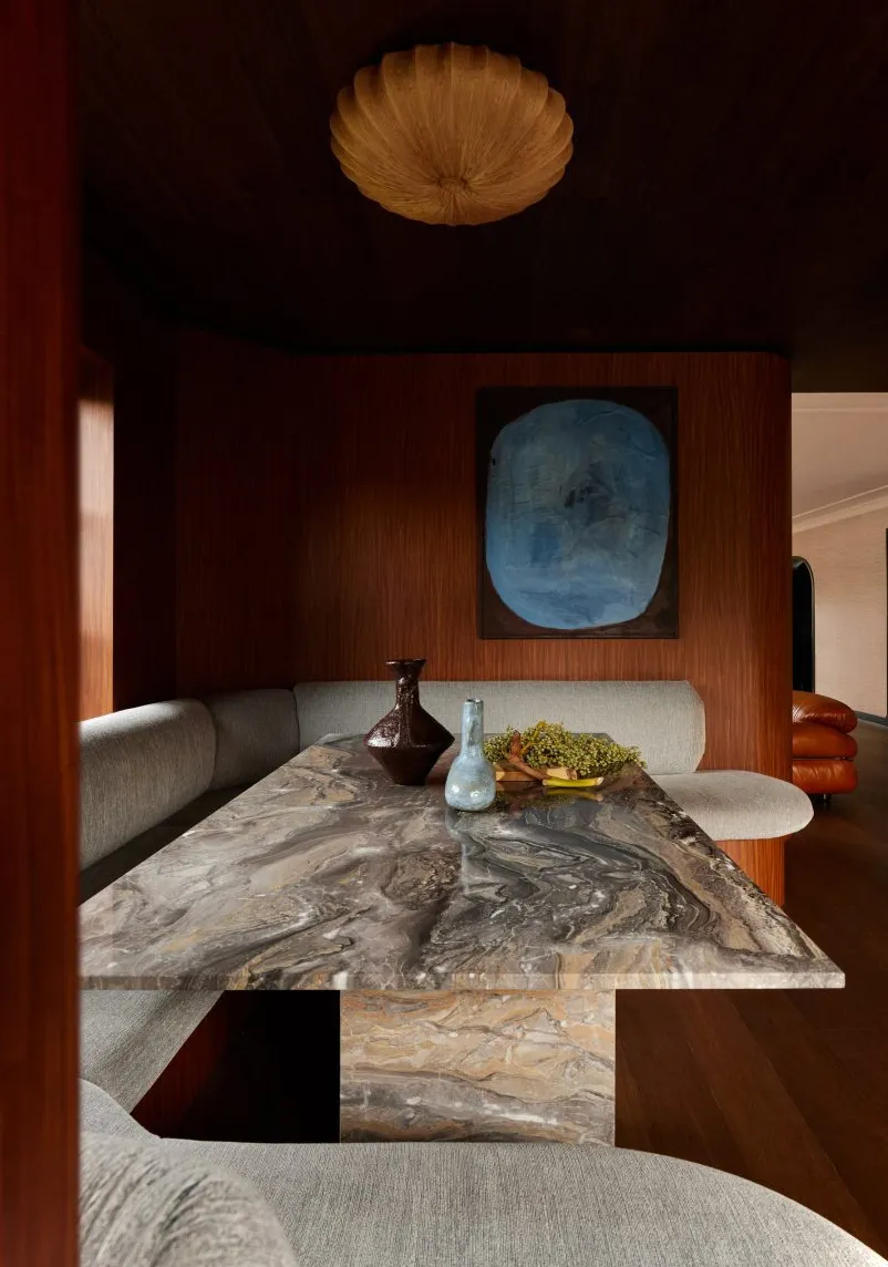 Rincón para sentarse revestido de madera con asientos tapizados y una mesa de mármol de DAB Studio