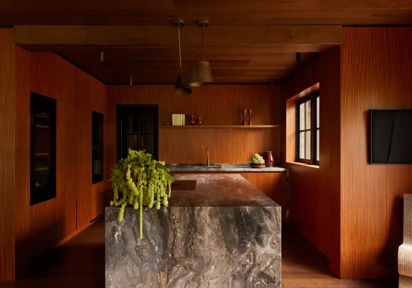 Interior de cocina revestido de madera con isla de mármol de DAB Studio