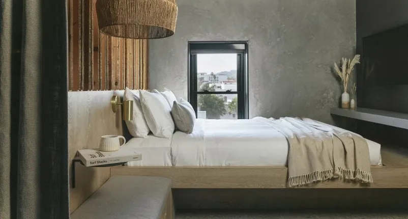 Un dormitorio con paredes grises y lámpara de ratán.