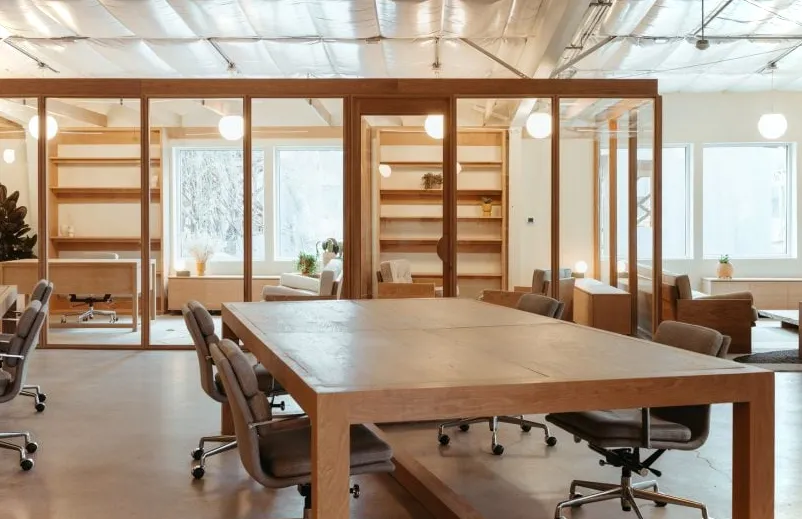 Espacio de trabajo abierto con grandes mesas de madera.