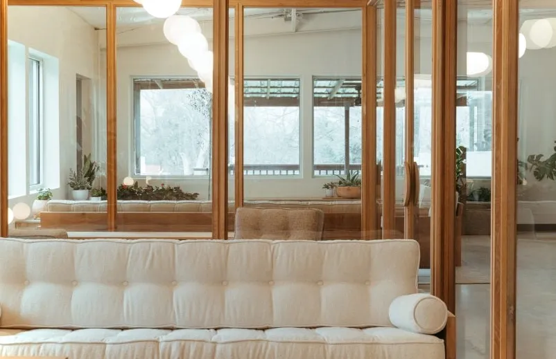Sofá beige frente a oficinas con paredes de vidrio