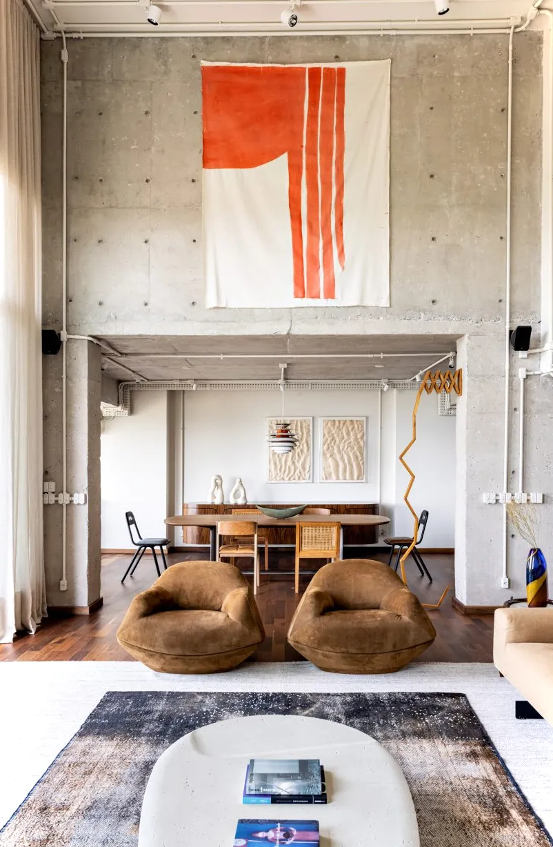 Sala de estar del apartamento Gale con sillones marrones y paredes de hormigón