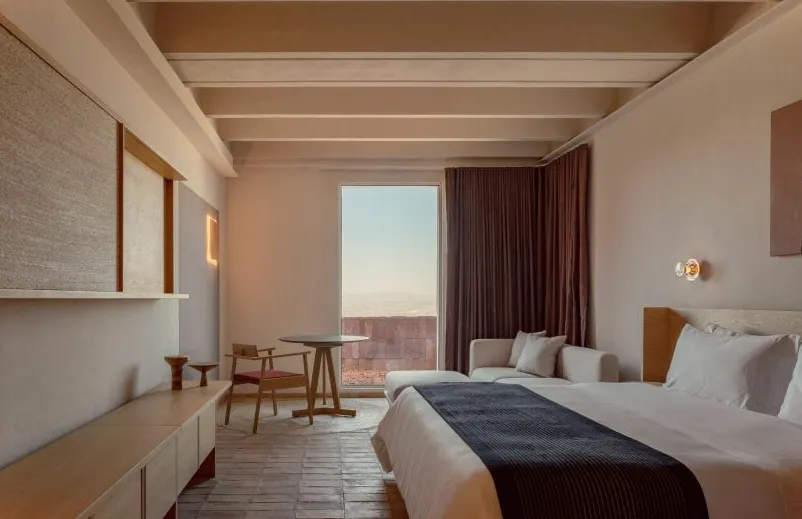 Un dormitorio decorado con textiles beige y paredes con toques en tonos tierra.