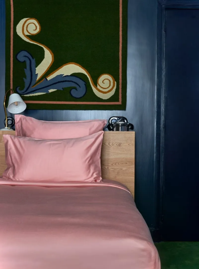 Sábanas de satén rosa en la cama en un hotel de París
