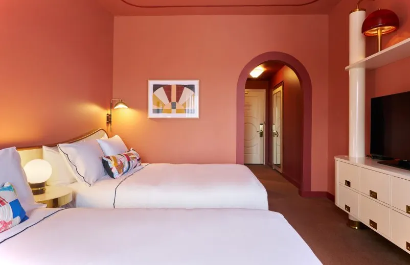 Habitación de hotel color terracota con dos camas tamaño queen
