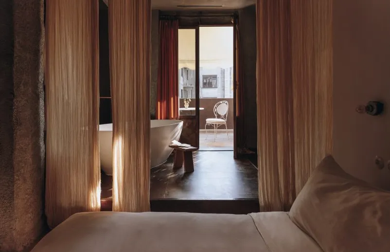 Dormitorio oscuro en tonos rojos en el hotel Mona de Atenas con bañera independiente