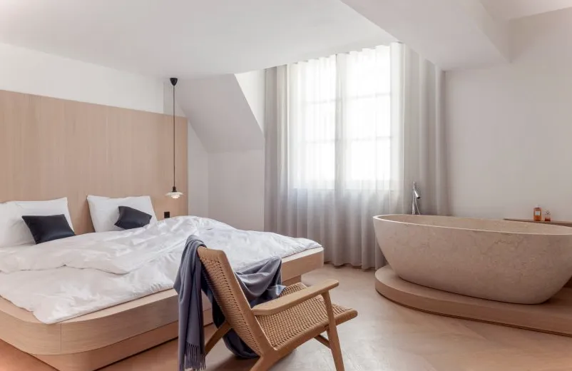Apartamento de un dormitorio Nicolai Paris de NOA con baño sobre escalón de madera y cama doble con ropa de cama blanca