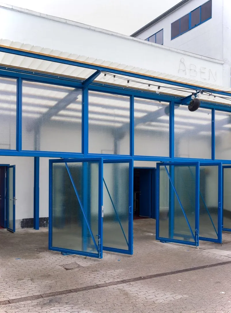 Puertas con borde azul en la cervecería ÅBEN diseñadas por Pihlmann Architects