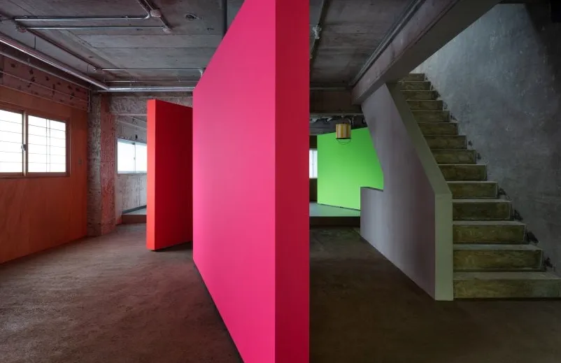 Tabiques giratorios de color rosa, naranja y verde en un apartamento de hormigón de AB Rogers