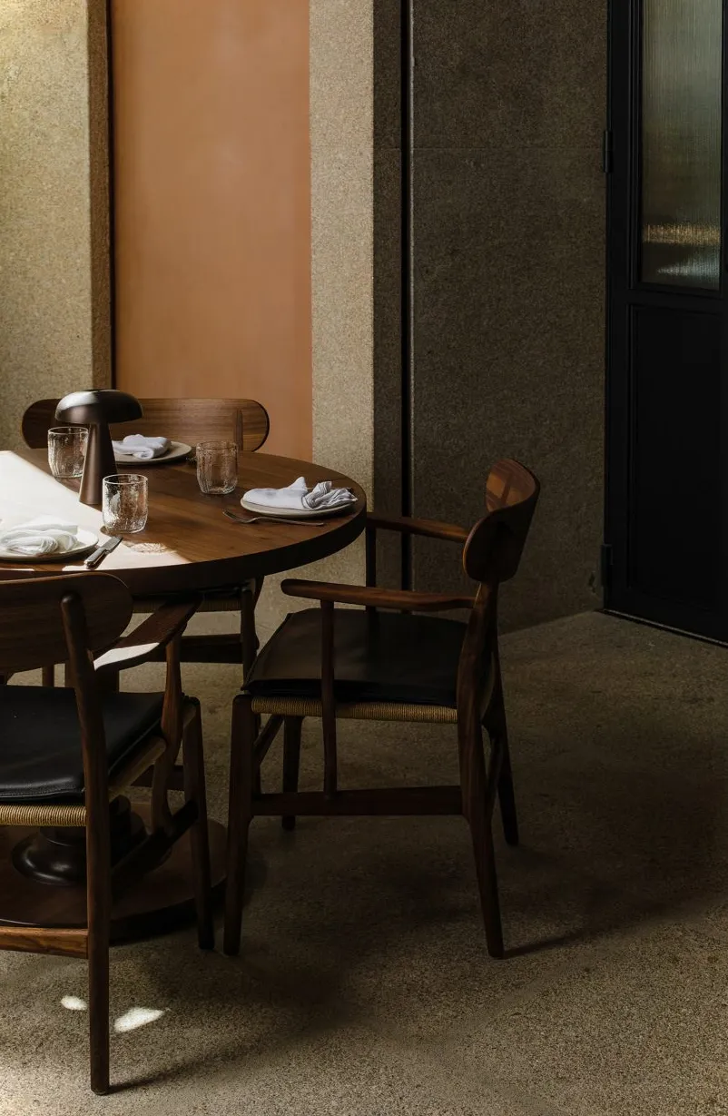 Pared enyesada y mesa de madera en el interior del restaurante Porto.