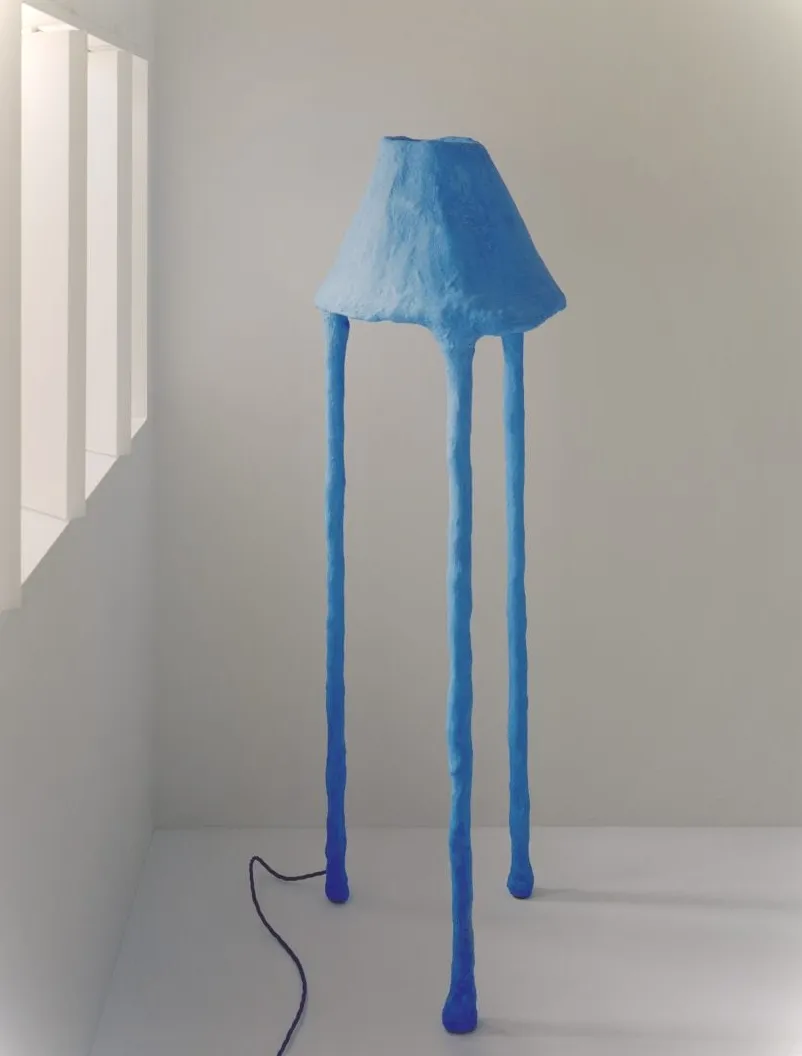 Lámpara de pie azul con forma de seta sobre un fondo blanco