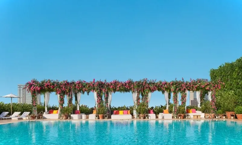 Terraza en la piscina con cabañas cubiertas de flores.