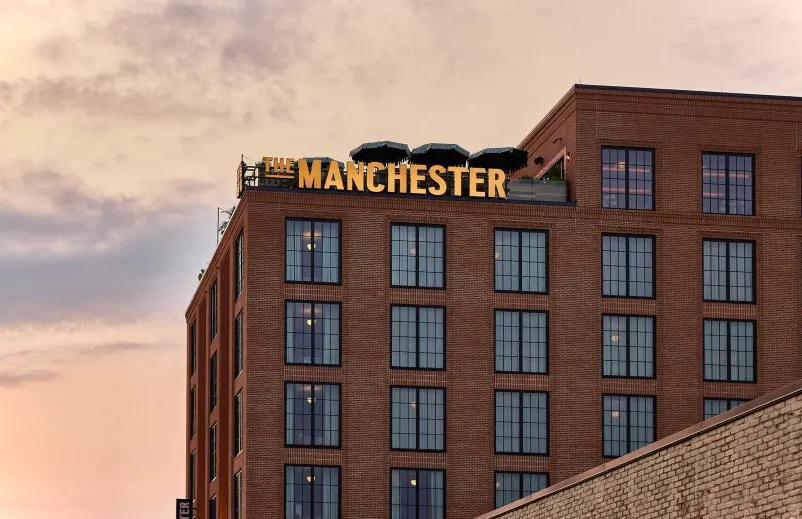 Vista exterior del edificio de ladrillo con el cartel de Manchester en amarillo