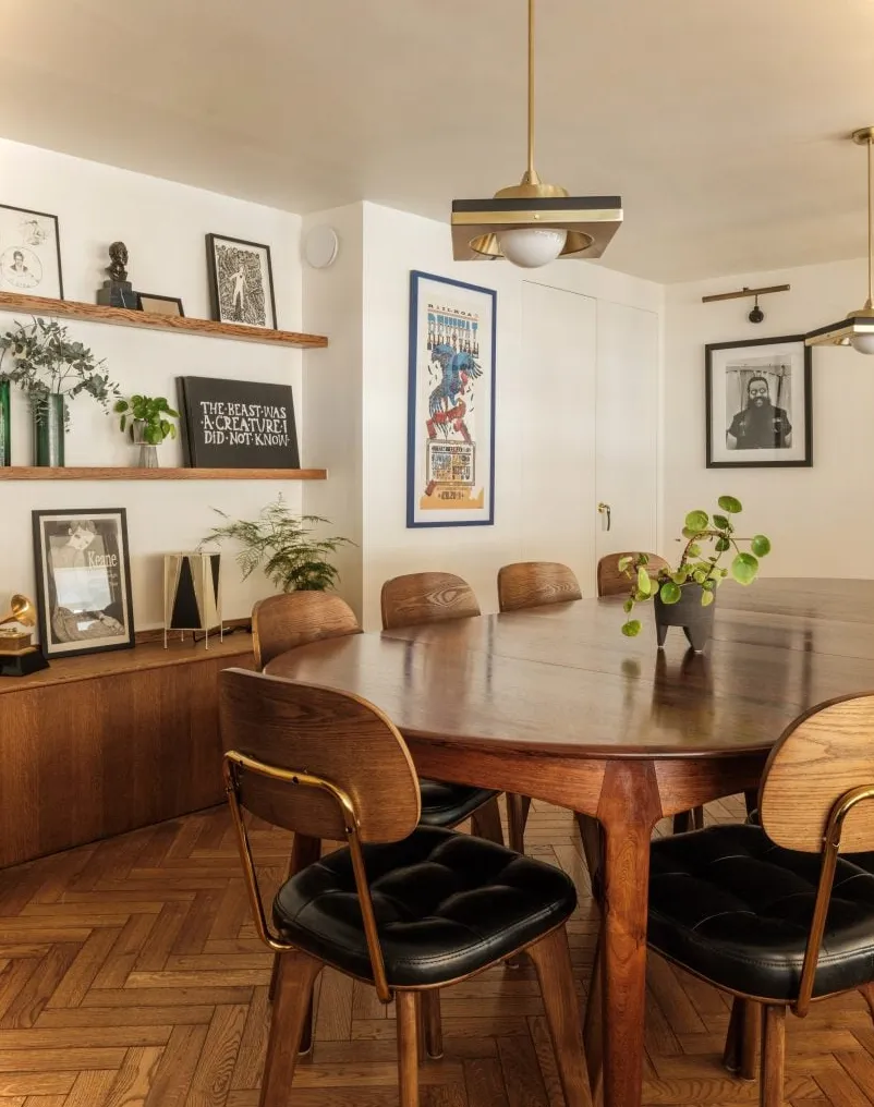 Sala de reuniones de oficina con suelo de parquet, mesa de madera y sillas de madera con asientos tapizados en negro