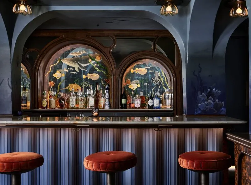 Área de bar azul oscuro con obras de arte en espejo acuático